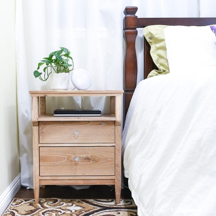A bedroom with a bed and wood nightstand