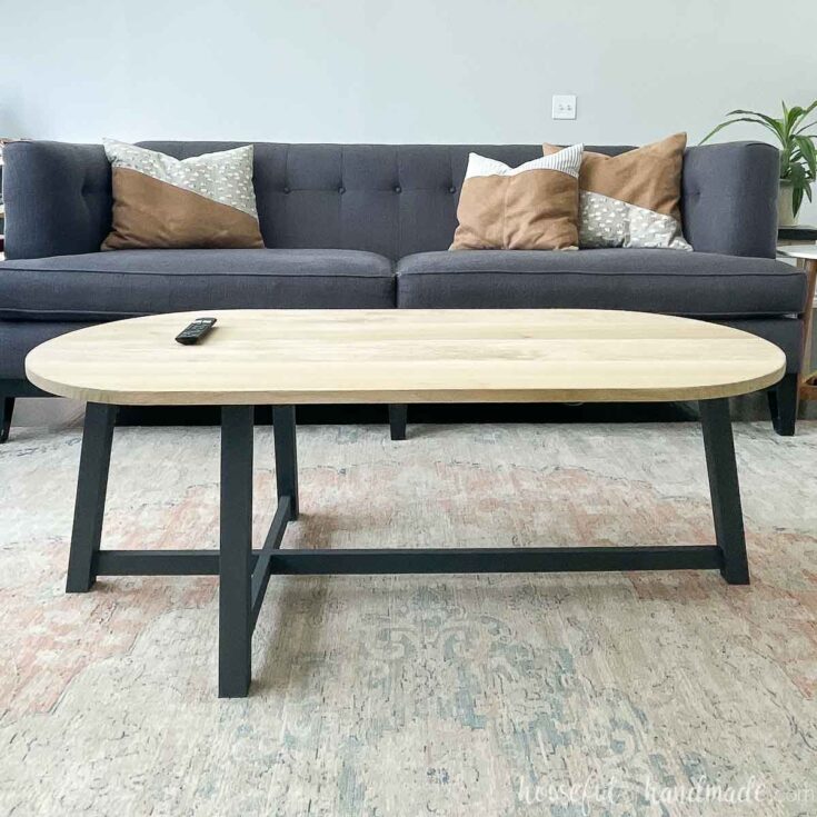 oval coffee table with angled black legs in front of sofa