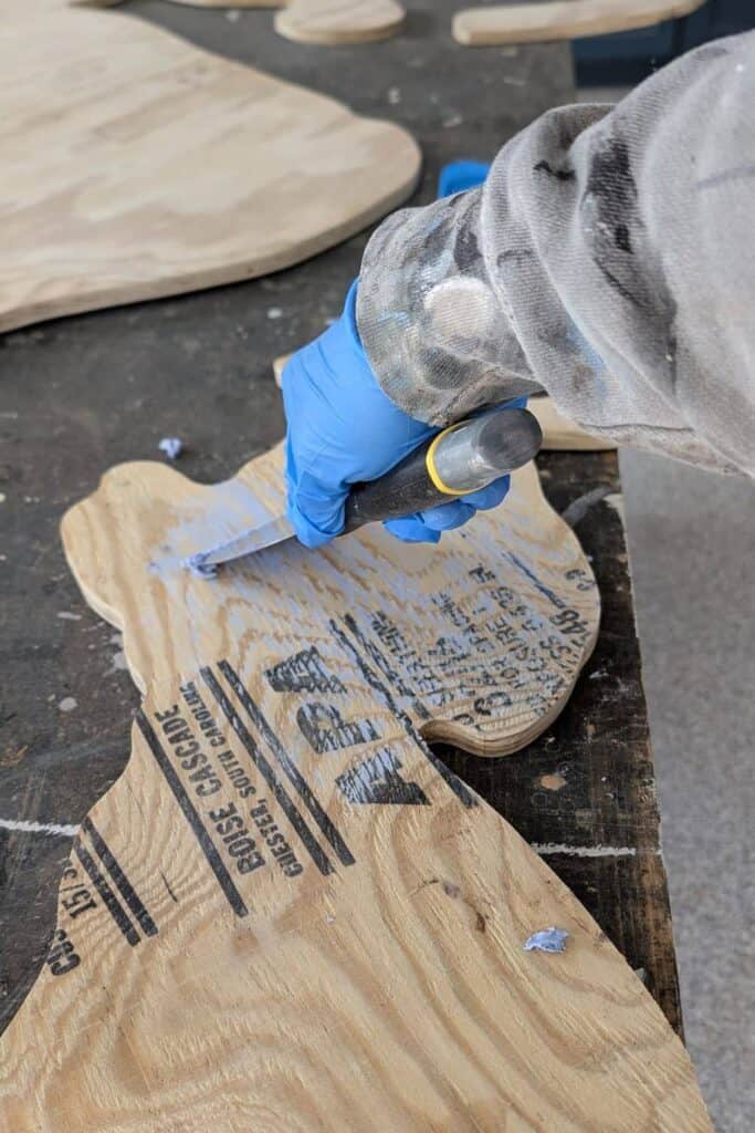 using spackle knife to add spackle to plywood