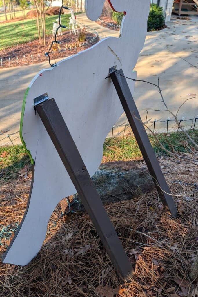 back of DIY Grinch decoration showing the 2x4 supports and the placement of the hinges